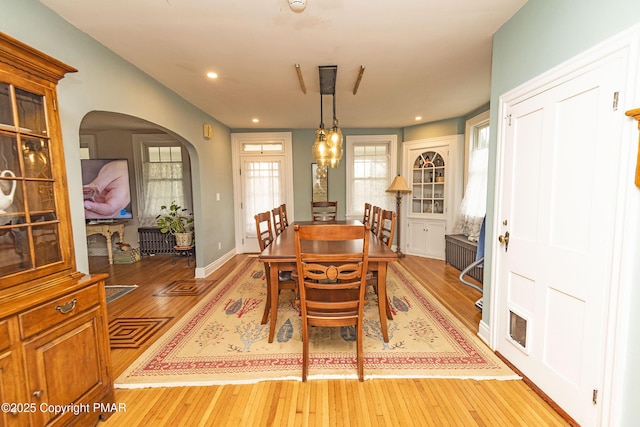 dining space with light wood-type flooring, visible vents, arched walkways, and recessed lighting