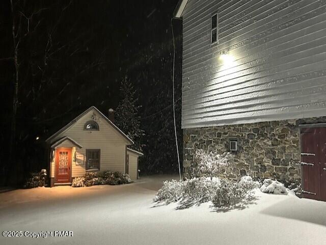 view of snow covered exterior with stone siding