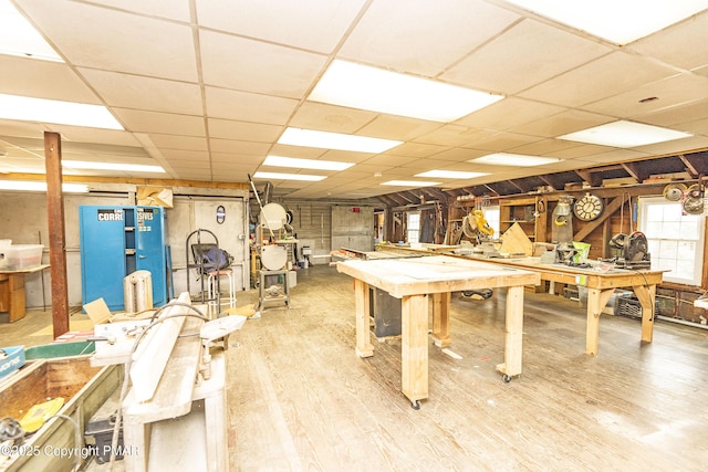 game room featuring a drop ceiling, a workshop area, and wood finished floors