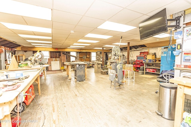 miscellaneous room with a paneled ceiling, a workshop area, and wood finished floors