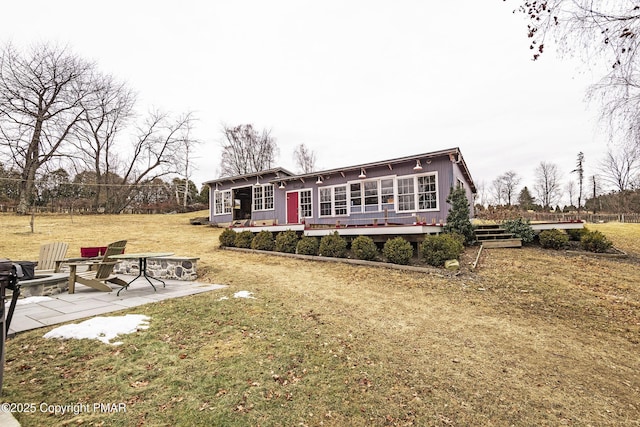 view of front facade featuring a patio, a sunroom, a front yard, and an outdoor fire pit