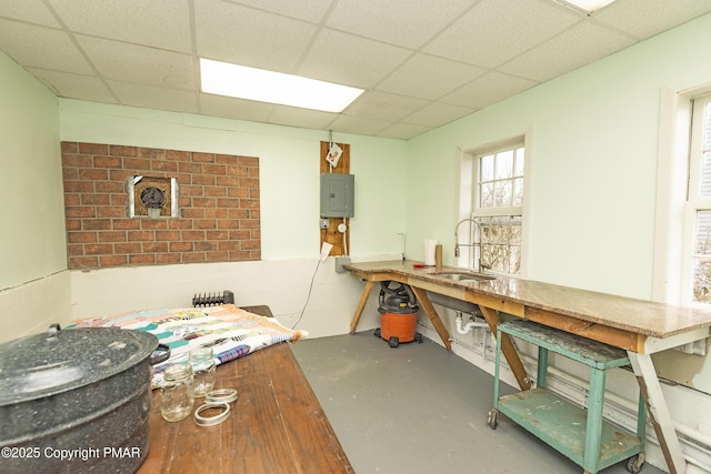 interior space featuring finished concrete flooring, electric panel, a drop ceiling, and a sink