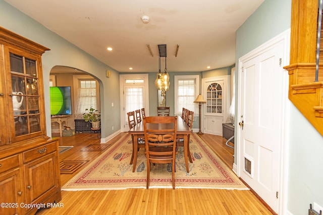 dining space featuring arched walkways, visible vents, light wood finished floors, and recessed lighting