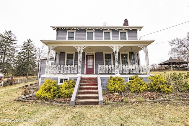 view of front of house featuring a porch, stairway, and a chimney