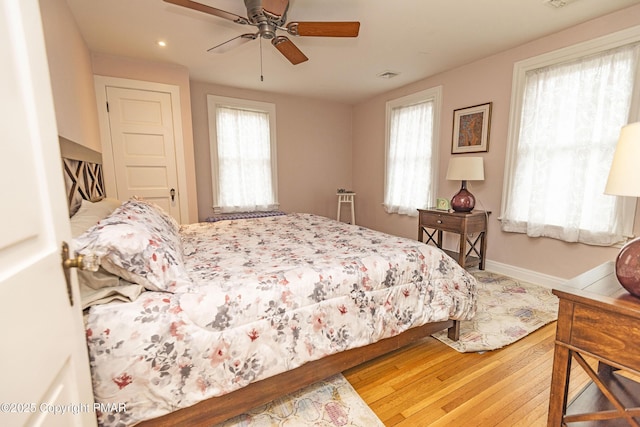 bedroom featuring ceiling fan, wood-type flooring, and multiple windows