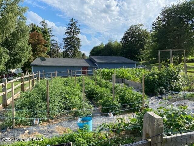 back of property featuring fence and a vegetable garden