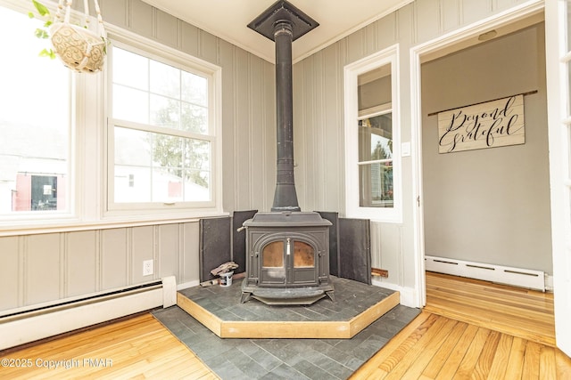 details featuring a wood stove, a baseboard radiator, crown molding, and wood finished floors