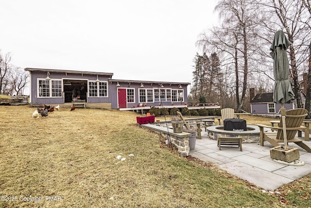 rear view of house featuring a fire pit, a lawn, a patio area, and a sunroom