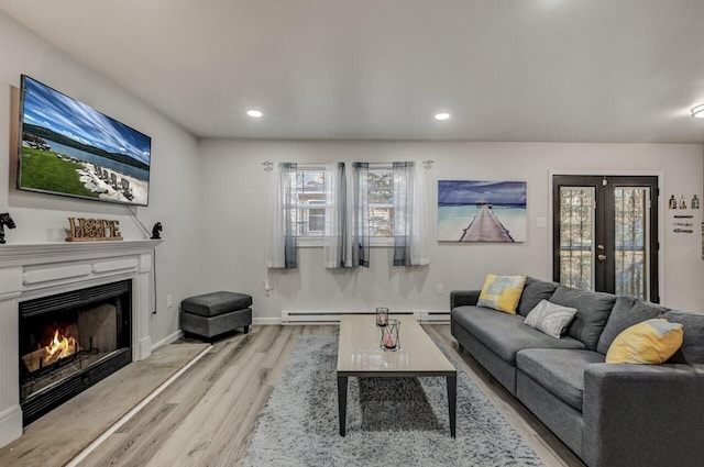 living room featuring light wood-type flooring, recessed lighting, french doors, a lit fireplace, and baseboard heating