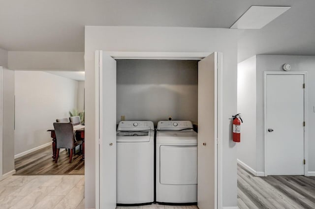 laundry room featuring light wood finished floors, laundry area, baseboards, and separate washer and dryer