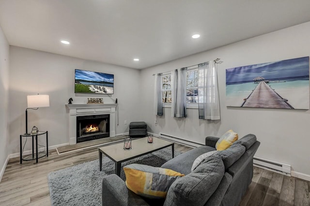 living area with wood finished floors, a lit fireplace, and a baseboard radiator