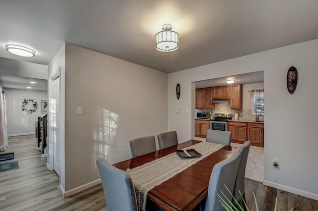 dining area with light wood-style floors and baseboards