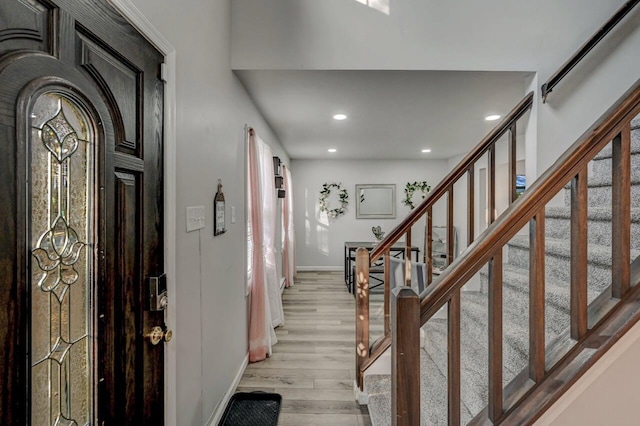 foyer entrance with light wood finished floors, stairway, recessed lighting, and baseboards