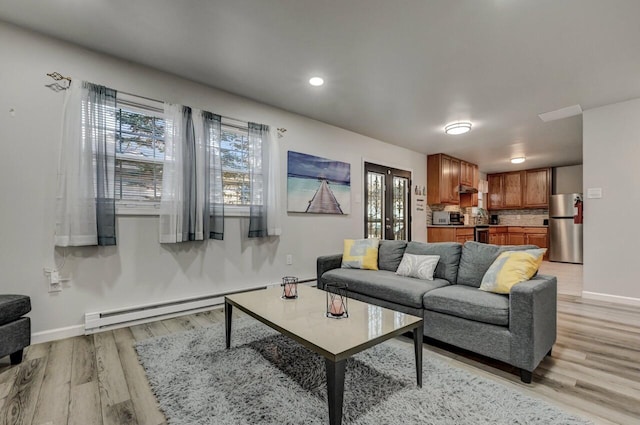 living area with recessed lighting, a baseboard heating unit, baseboards, and light wood-style floors