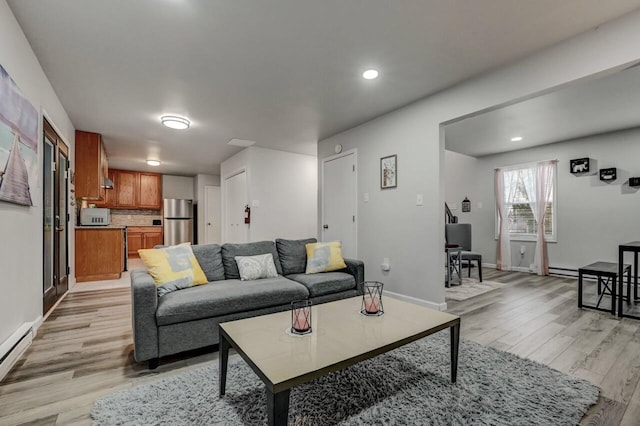 living area with recessed lighting, a baseboard heating unit, baseboards, and light wood-style floors