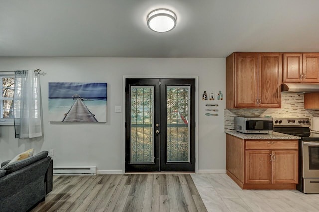 kitchen with under cabinet range hood, a baseboard heating unit, backsplash, french doors, and appliances with stainless steel finishes