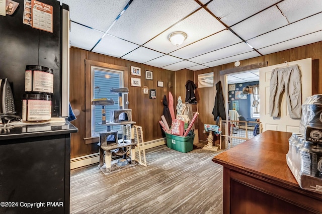 office area with a paneled ceiling, wood walls, and wood finished floors