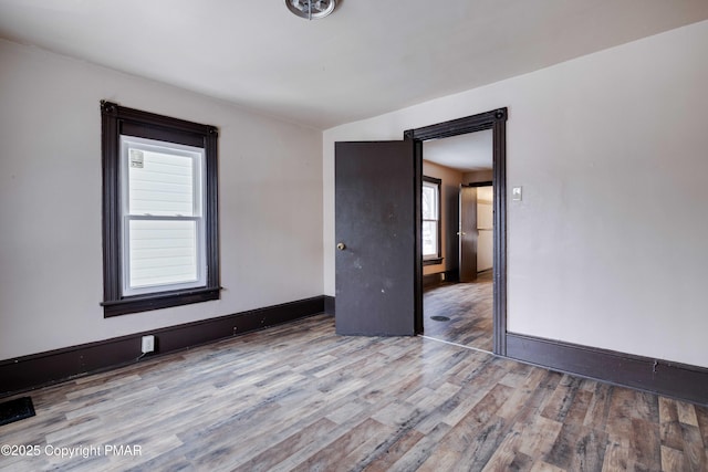 spare room featuring baseboards and wood finished floors