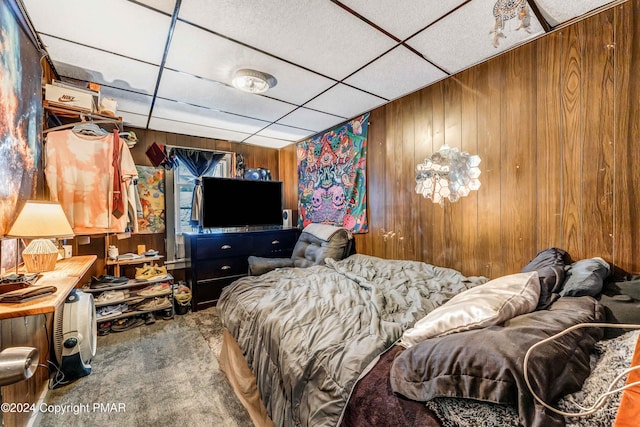 bedroom featuring a paneled ceiling, wooden walls, and carpet