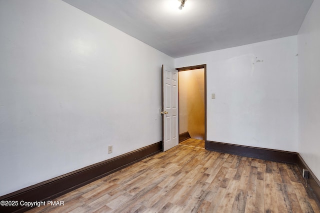 unfurnished room with baseboards and light wood finished floors