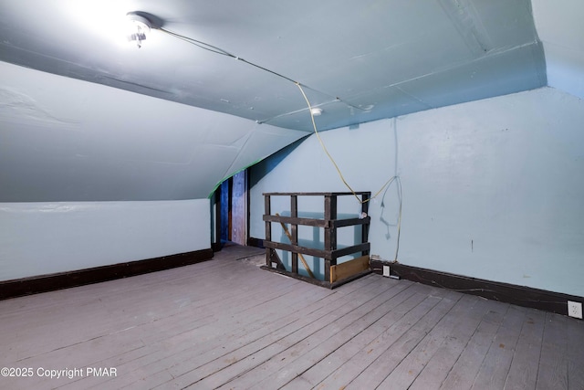 additional living space with wood-type flooring, baseboards, and vaulted ceiling