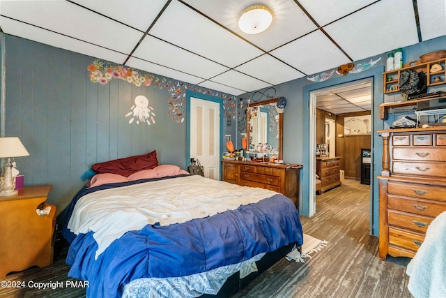 bedroom with a drop ceiling and wood finished floors