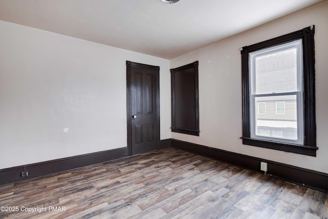 empty room featuring wood finished floors and baseboards