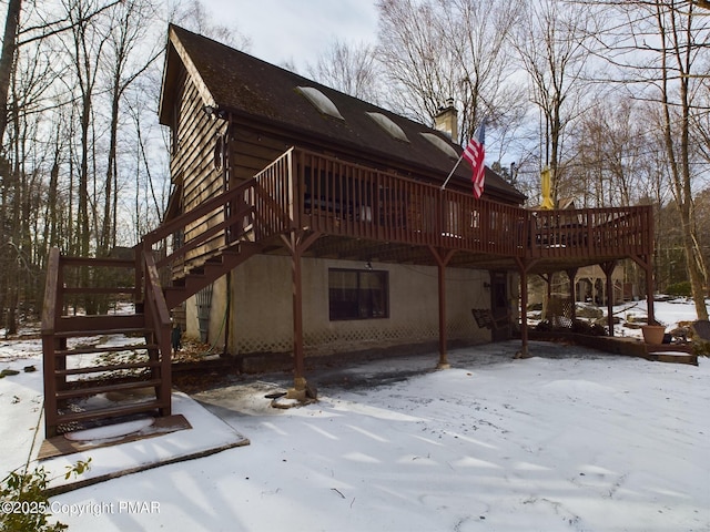 snow covered house with a wooden deck