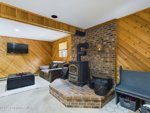 living room with a baseboard heating unit, wooden walls, light carpet, and a wood stove