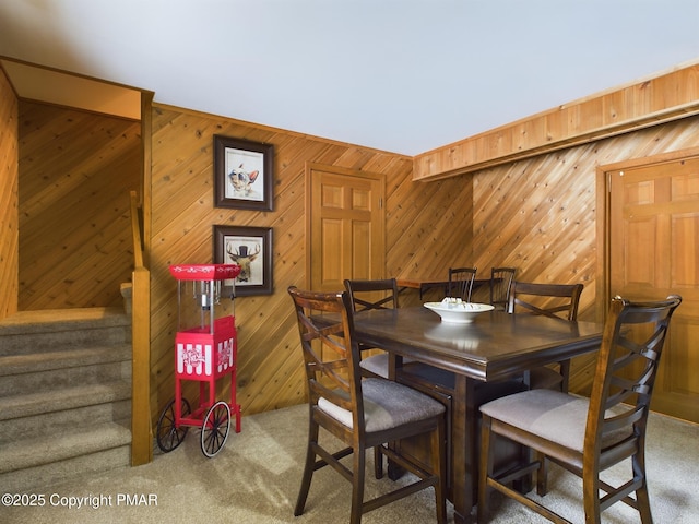 dining room featuring wooden walls and carpet