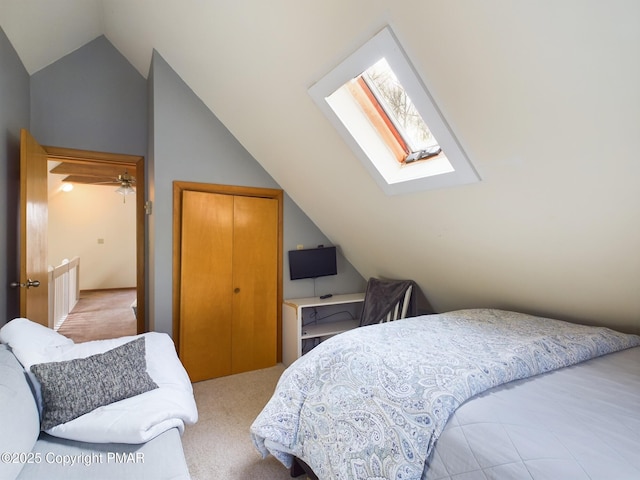 bedroom with lofted ceiling with skylight, light colored carpet, and a closet