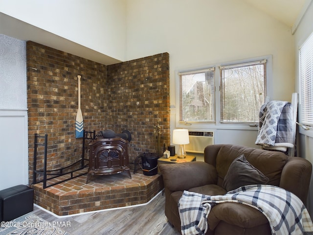 living room featuring hardwood / wood-style floors, a wall mounted air conditioner, high vaulted ceiling, and a wood stove