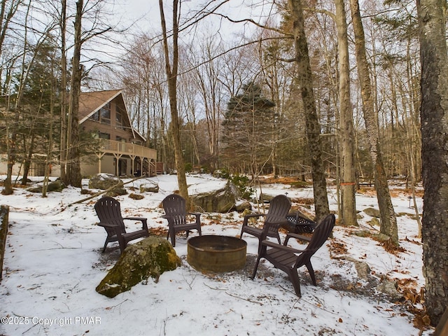 snowy yard with a wooden deck and a fire pit