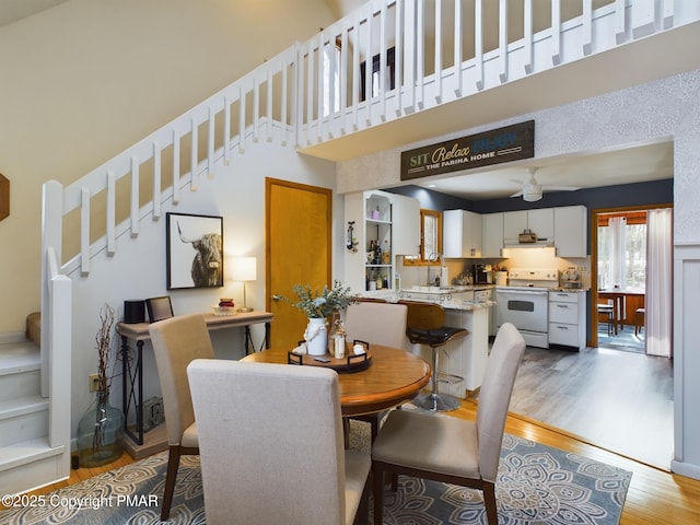 dining area with a towering ceiling and light hardwood / wood-style flooring