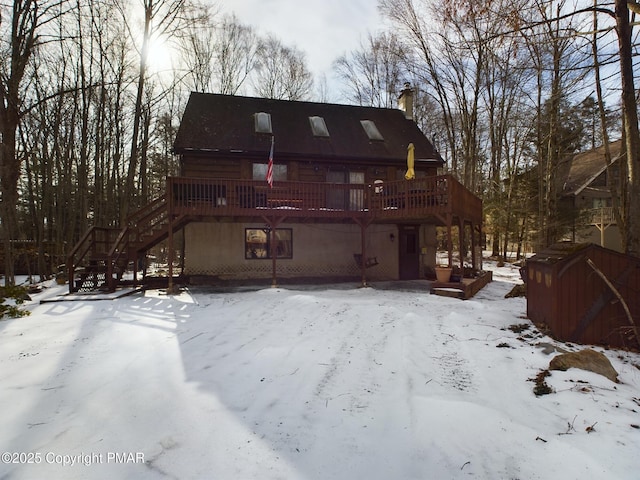 snow covered back of property featuring a wooden deck