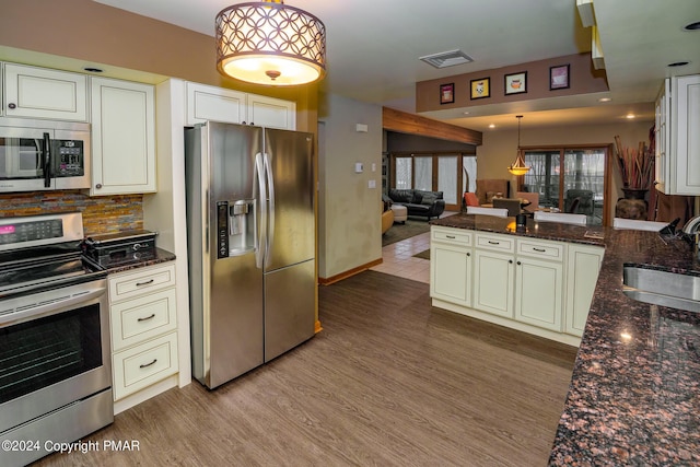 kitchen featuring visible vents, open floor plan, appliances with stainless steel finishes, wood finished floors, and a sink