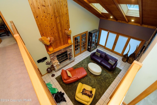 living area featuring french doors, a skylight, a fireplace, baseboards, and a towering ceiling