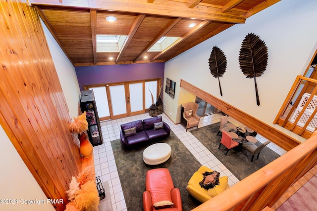 living area featuring tile patterned floors, beam ceiling, a skylight, and wooden ceiling