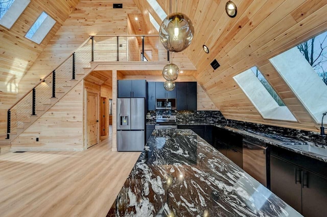 4142 Calendula Ct, Pocono Pines, PA 18350 - kitchen featuring appliances with stainless steel finishes, a skylight, wooden ceiling, wooden walls, and dark stone counters