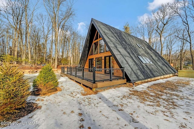 exterior space with a shingled roof and a wooden deck