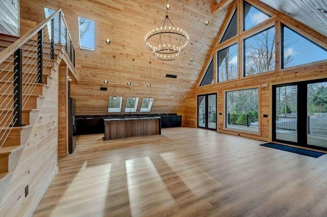 4142 Calendula Ct, Pocono Pines, PA 18350 - unfurnished living room with high vaulted ceiling, plenty of natural light, a chandelier, wood walls, and light wood-type flooring