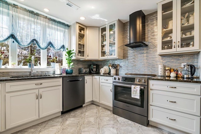 116 Red Bud Ln, Kunkletown, PA 18058 - kitchen featuring stainless steel appliances, wall chimney exhaust hood, tasteful backsplash, dark stone countertops, and glass insert cabinets
