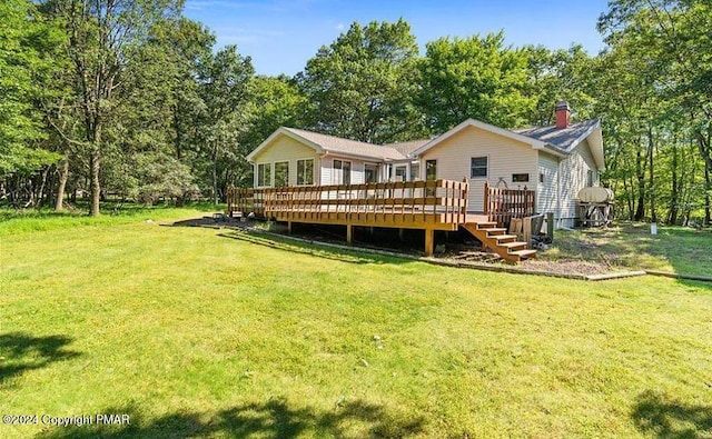 back of house featuring a yard, a deck, and a chimney