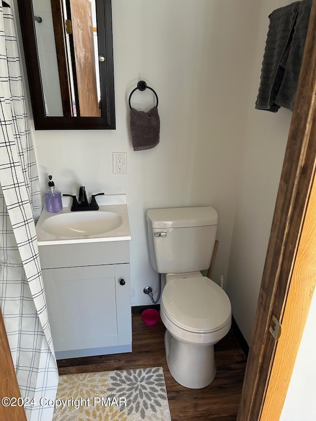 bathroom featuring baseboards, toilet, wood finished floors, and vanity