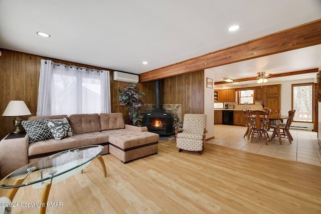 living area featuring light wood-type flooring, a wall mounted AC, recessed lighting, wood walls, and a wood stove