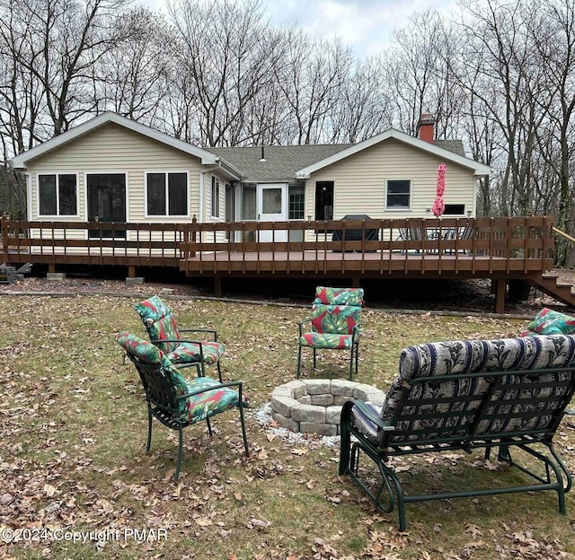 back of property featuring a chimney, a wooden deck, an outdoor fire pit, and roof with shingles