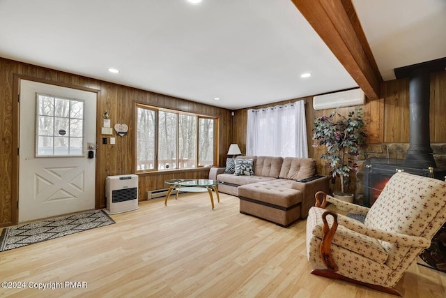 living area with wooden walls, light wood-style flooring, a wall mounted AC, and a wood stove