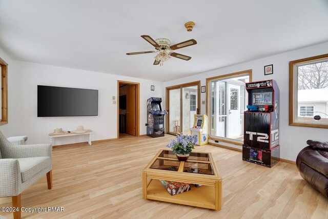 living room featuring wood finished floors, a ceiling fan, and baseboards