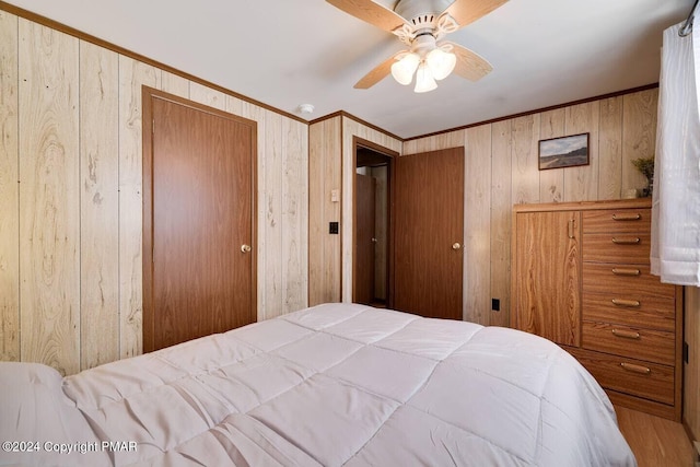 bedroom featuring a ceiling fan, wooden walls, and crown molding