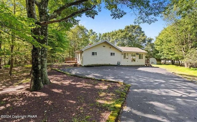 exterior space with an outdoor structure, driveway, and a shed